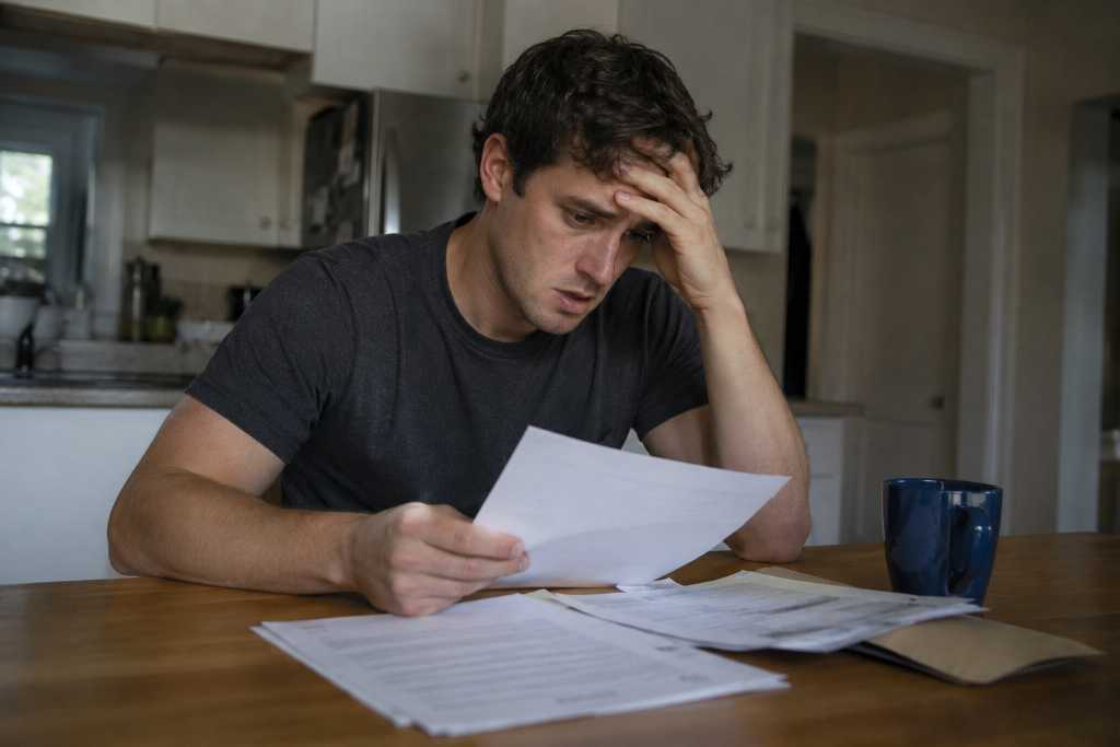 Stressed Man Reviewing Documents in Kitchen